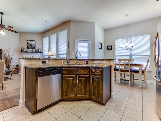 kitchen with light tile patterned floors, ceiling fan with notable chandelier, stainless steel appliances, a sink, and an island with sink