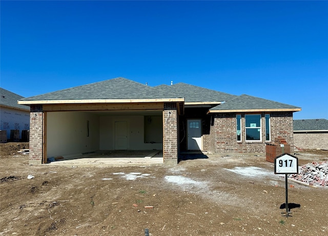 view of front facade with brick siding and roof with shingles