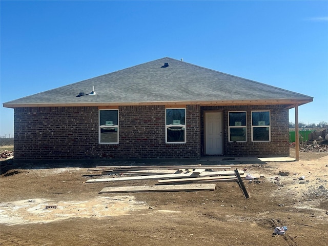 back of property with a shingled roof and brick siding