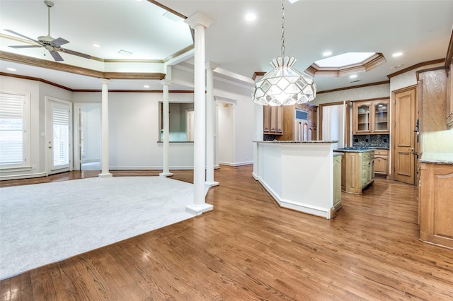 kitchen featuring ornate columns, glass insert cabinets, light wood finished floors, and a ceiling fan