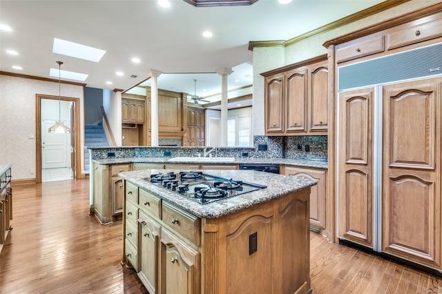 kitchen featuring a center island, crown molding, a sink, light wood-type flooring, and black appliances