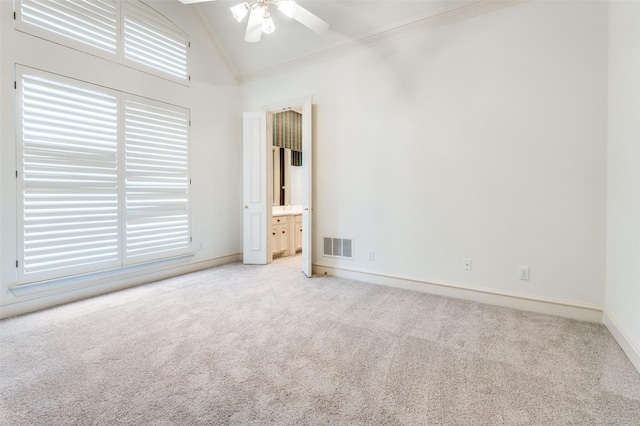 empty room with carpet flooring, a ceiling fan, baseboards, vaulted ceiling, and crown molding