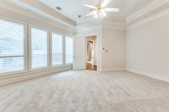 spare room featuring carpet floors, a raised ceiling, visible vents, and crown molding