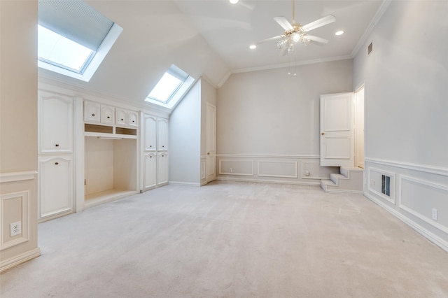 additional living space featuring vaulted ceiling with skylight, visible vents, a decorative wall, and light colored carpet