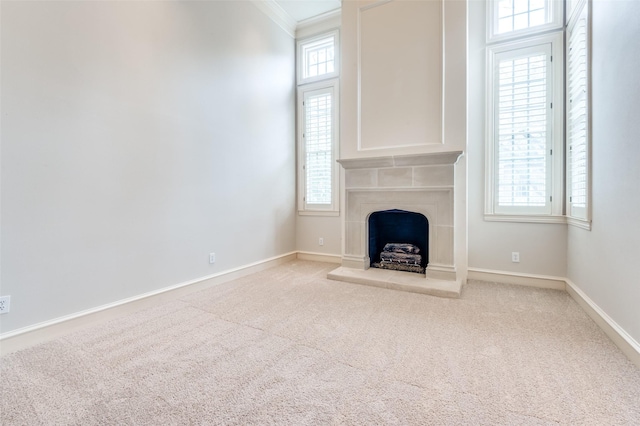 unfurnished living room featuring carpet floors, baseboards, a fireplace, and ornamental molding