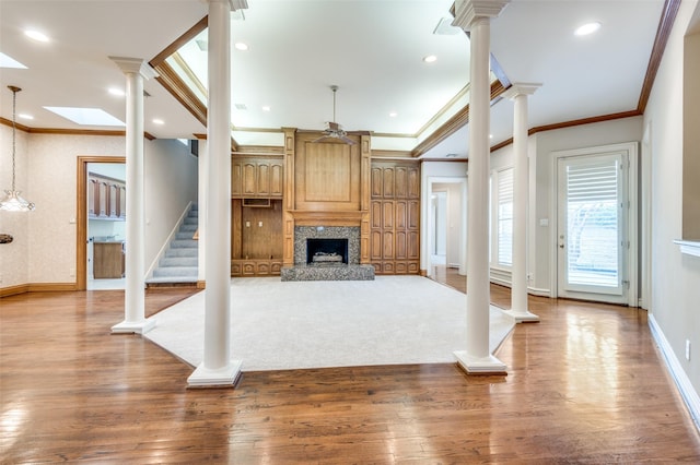 unfurnished living room with decorative columns, stairway, and wood finished floors