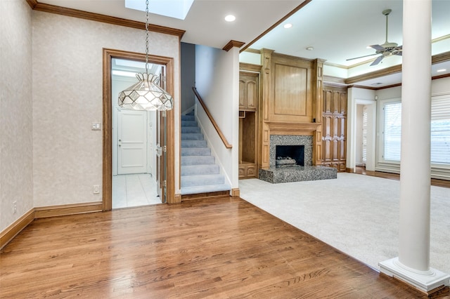 unfurnished living room with light wood-style floors, ceiling fan, stairway, and crown molding