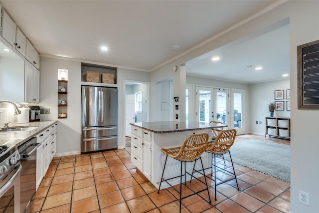 kitchen featuring ornamental molding, appliances with stainless steel finishes, a kitchen island, and a sink