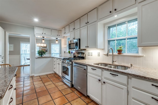 kitchen featuring stainless steel appliances, white cabinets, a sink, and backsplash