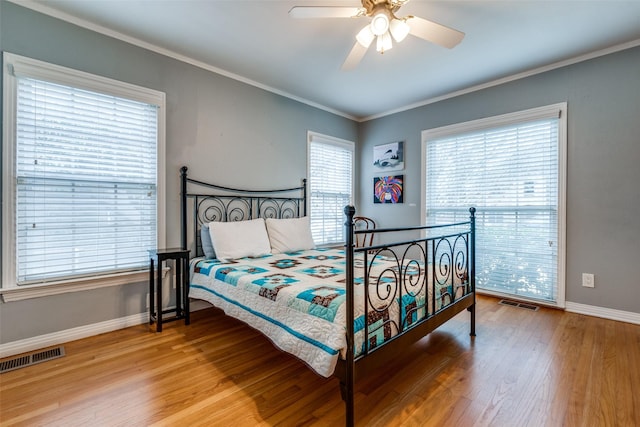 bedroom featuring baseboards, light wood-style flooring, visible vents, and crown molding