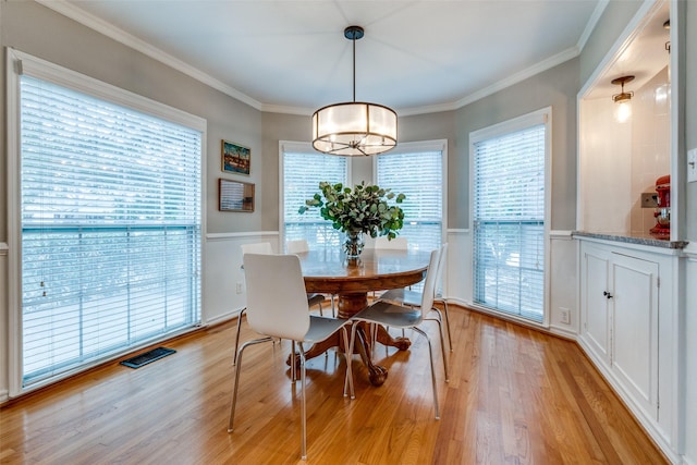 dining room with light wood-style floors, visible vents, and crown molding