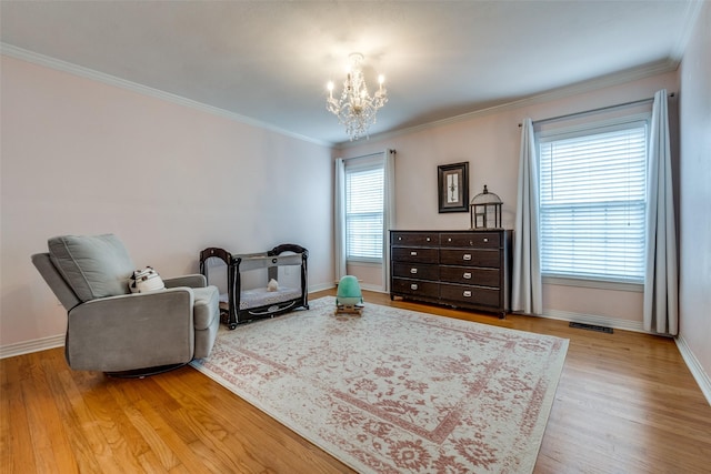 living area featuring crown molding, visible vents, wood finished floors, a chandelier, and baseboards