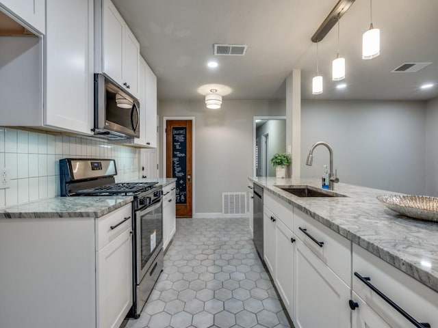 kitchen featuring tasteful backsplash, visible vents, stainless steel appliances, and a sink