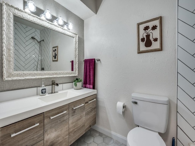 full bath with toilet, a tile shower, vanity, tile patterned flooring, and baseboards