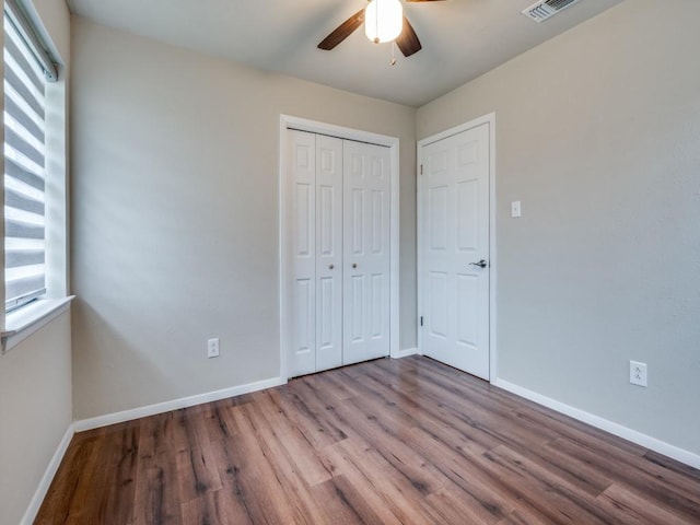 unfurnished bedroom featuring a ceiling fan, a closet, baseboards, and wood finished floors