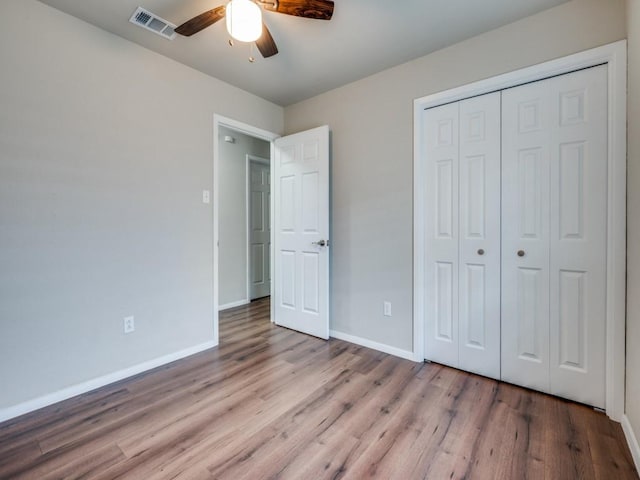 unfurnished bedroom featuring a closet, visible vents, baseboards, and wood finished floors