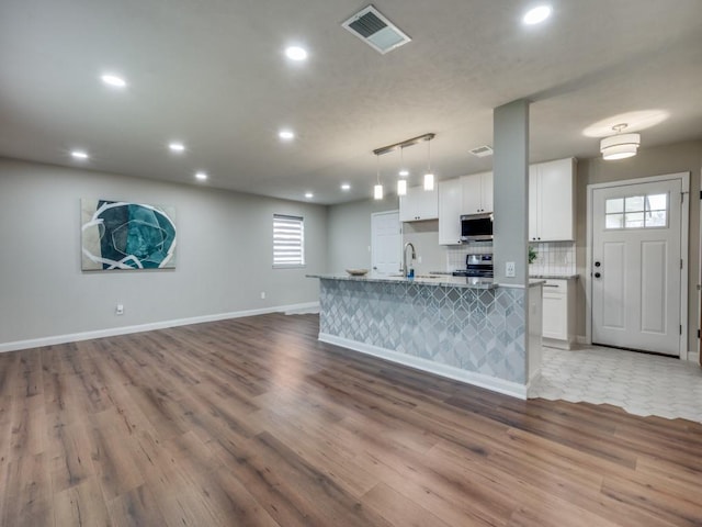 kitchen with stainless steel appliances, tasteful backsplash, visible vents, open floor plan, and white cabinetry