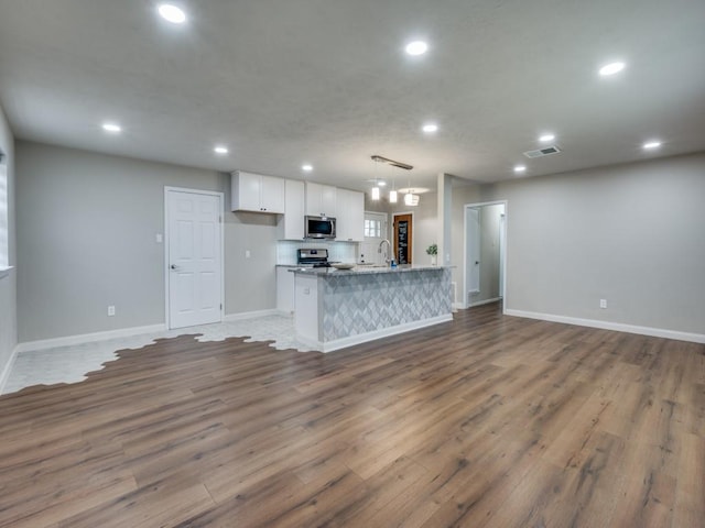 kitchen with visible vents, appliances with stainless steel finishes, open floor plan, white cabinetry, and recessed lighting