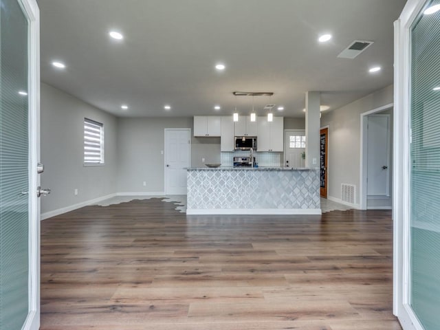 kitchen featuring stainless steel appliances, wood finished floors, visible vents, and white cabinets