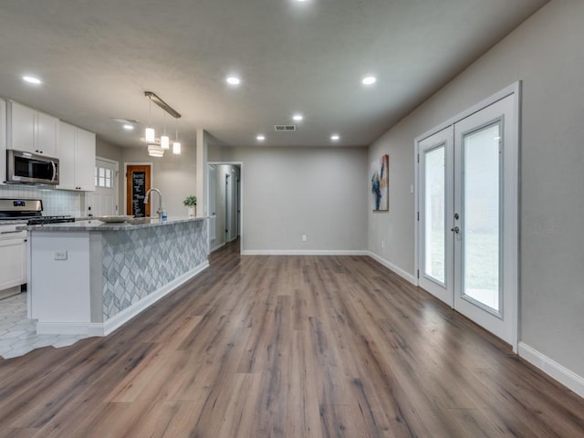 kitchen featuring stainless steel appliances, french doors, backsplash, and white cabinetry