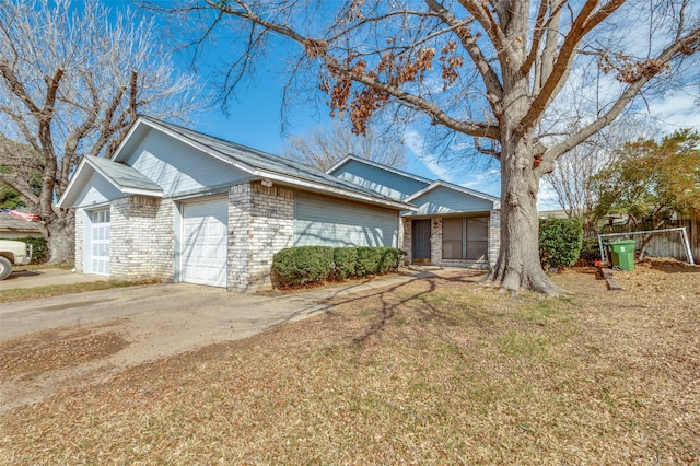 view of front of house with driveway, brick siding, a front lawn, and an attached garage