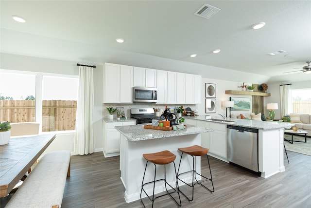 kitchen with appliances with stainless steel finishes, a breakfast bar, visible vents, and white cabinets