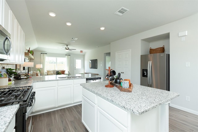 kitchen featuring visible vents, appliances with stainless steel finishes, open floor plan, a peninsula, and a sink