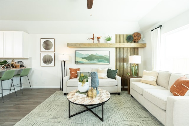 living area featuring lofted ceiling, baseboards, and wood finished floors