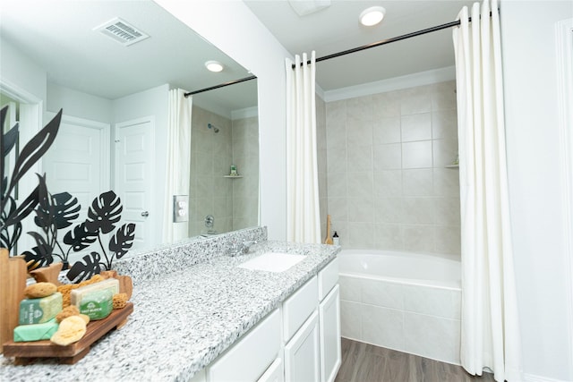 full bath with visible vents, tiled shower / bath combo, vanity, and wood finished floors