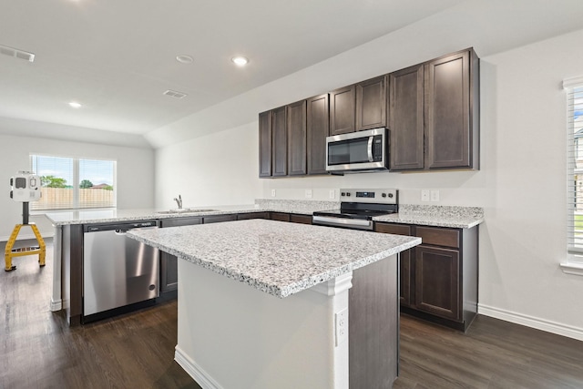 2400 Dahlia Dr, Fort Worth, TX 76123 - kitchen featuring appliances with stainless steel finishes, a peninsula, a sink, dark brown cabinetry, and dark wood-style floors