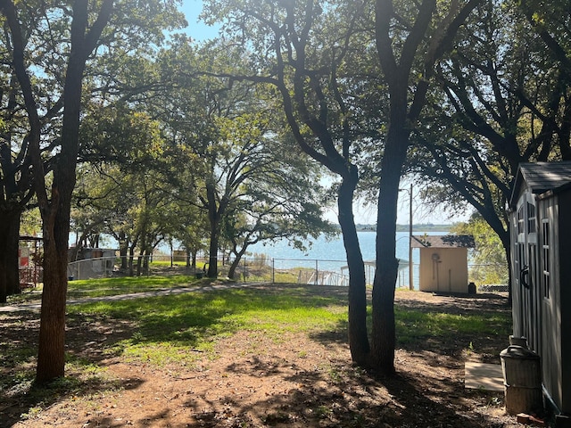 view of yard with a water view, a storage unit, fence, and an outdoor structure