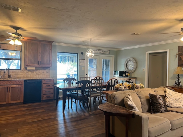 living area with ceiling fan, a wealth of natural light, dark wood finished floors, and visible vents