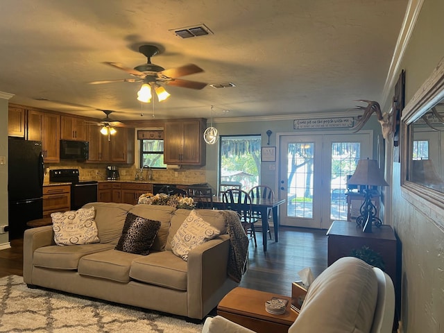 living room featuring dark wood-type flooring, visible vents, crown molding, and a textured ceiling