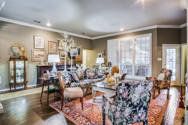 living area with ornamental molding, wood finished floors, visible vents, and baseboards