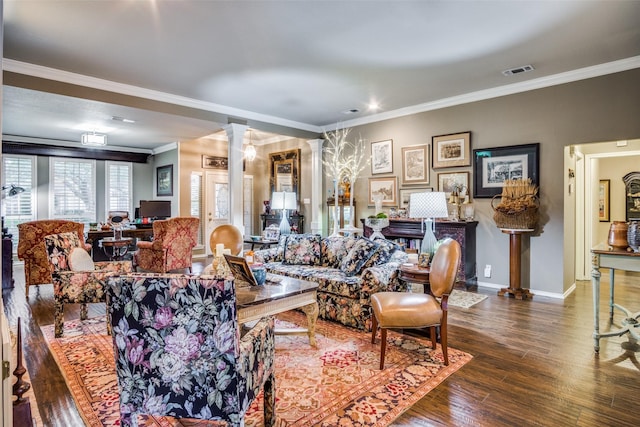 living room featuring wood finished floors, visible vents, baseboards, ornamental molding, and decorative columns