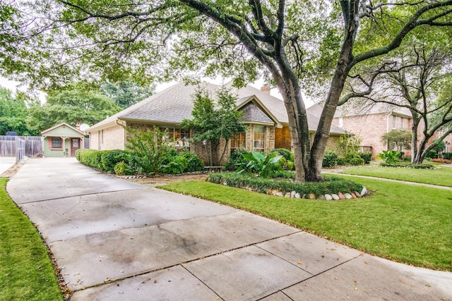 view of front of home with concrete driveway, stone siding, fence, a front yard, and brick siding