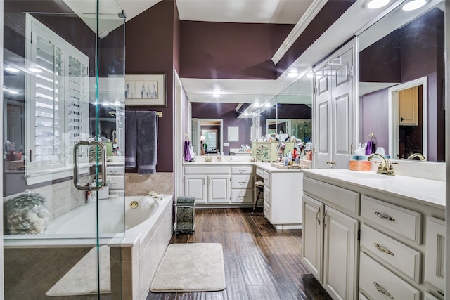 bathroom with wood finished floors, two vanities, a sink, and a bath