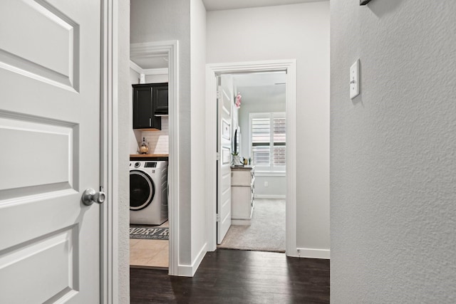 hallway featuring washer / dryer, dark wood-type flooring, a textured wall, and baseboards