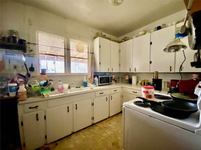 kitchen featuring electric stove, stainless steel microwave, light countertops, and white cabinetry