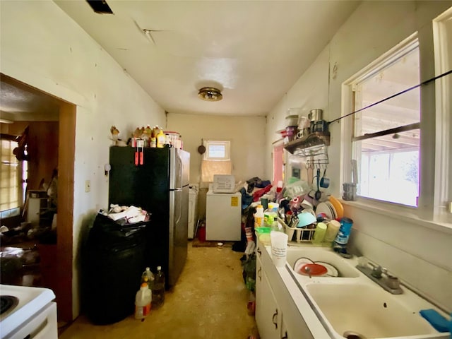 kitchen featuring washer / dryer, white cabinetry, a sink, and freestanding refrigerator