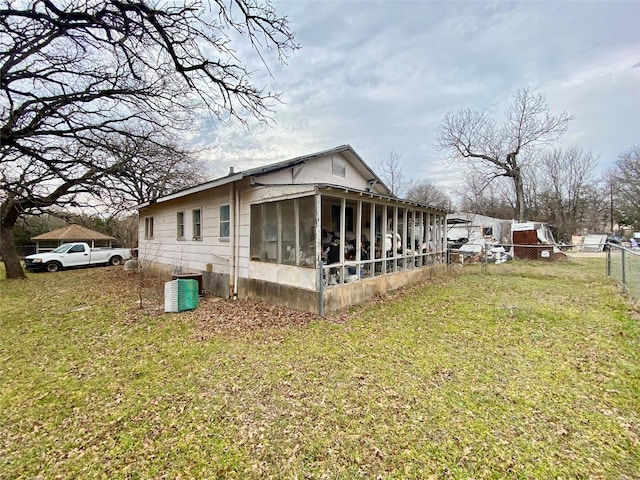 view of side of property featuring a sunroom, a yard, central air condition unit, and fence