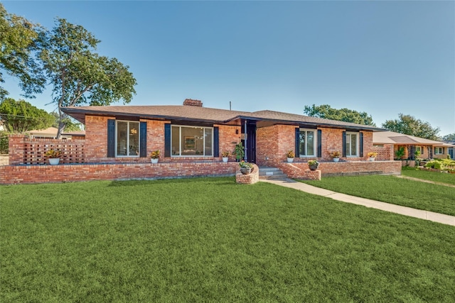 ranch-style house with brick siding, a chimney, and a front yard