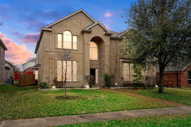 traditional-style home featuring a front yard, cooling unit, and brick siding