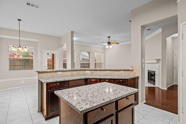 kitchen with arched walkways, visible vents, a tile fireplace, and light tile patterned floors