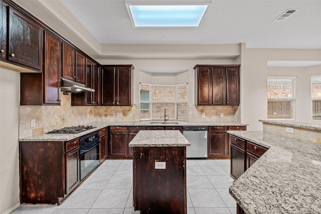 kitchen with under cabinet range hood, a sink, visible vents, appliances with stainless steel finishes, and a center island