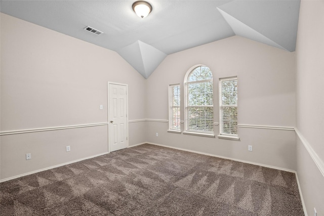 empty room with baseboards, visible vents, vaulted ceiling, and carpet flooring