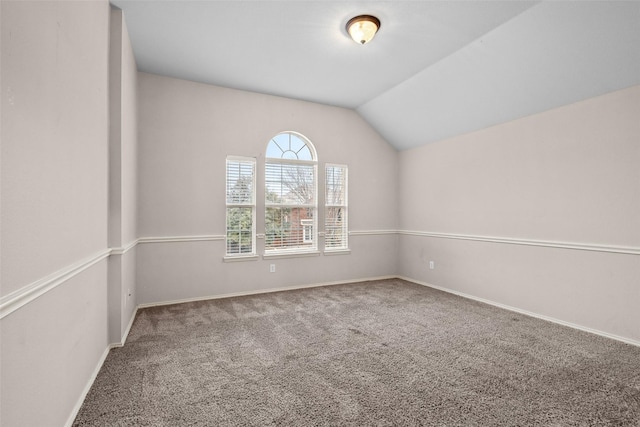 spare room featuring baseboards, vaulted ceiling, and carpet flooring