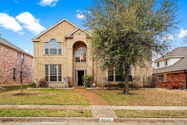 traditional-style home featuring brick siding and a front lawn