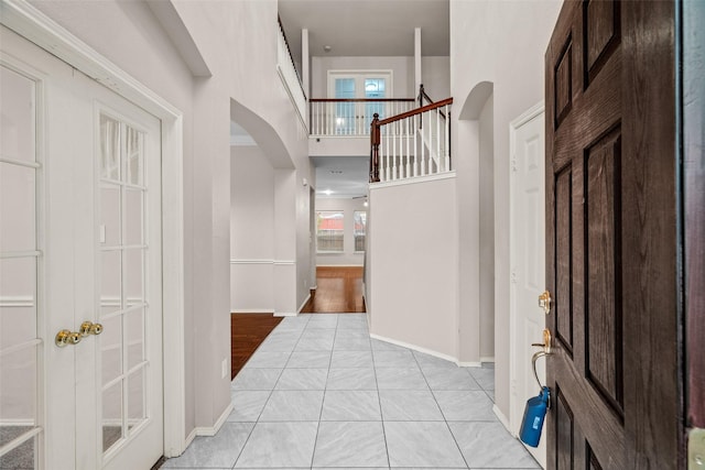 entrance foyer featuring arched walkways, plenty of natural light, and a towering ceiling