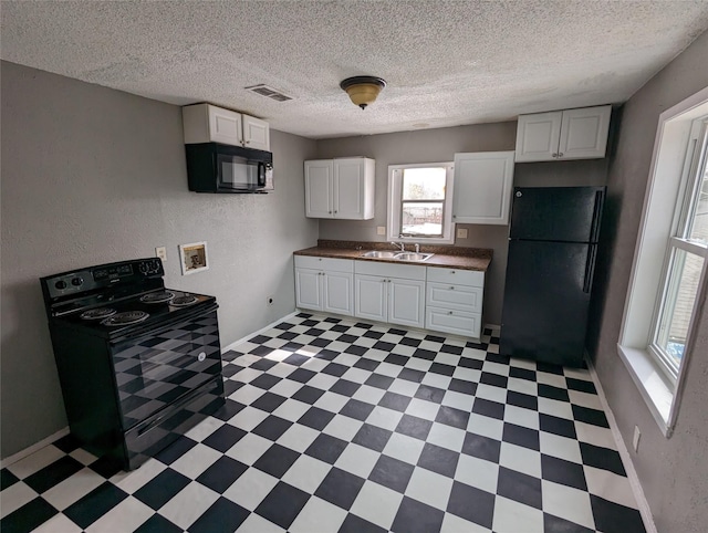 kitchen featuring visible vents, white cabinets, light floors, black appliances, and a sink